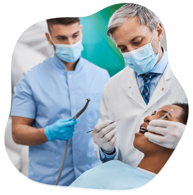 Dentista con enfermero revisando a paciente